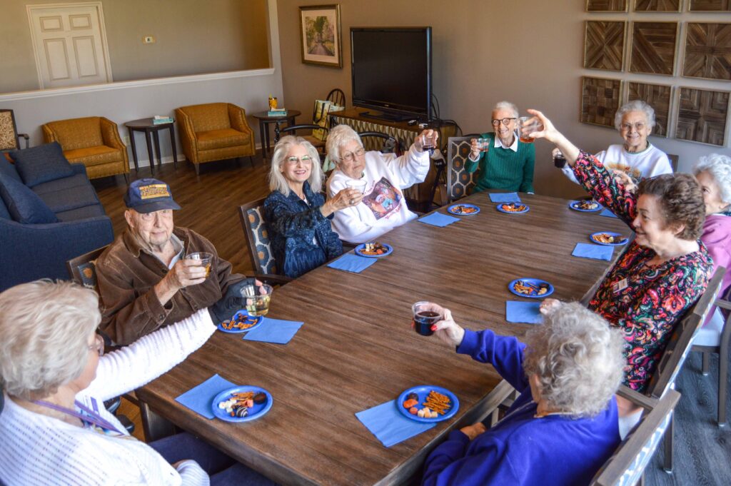 Residents sit around a table with refreshments during a social gathering at Inspirations of Mount Washington, a senior living community in Louisville, KY.