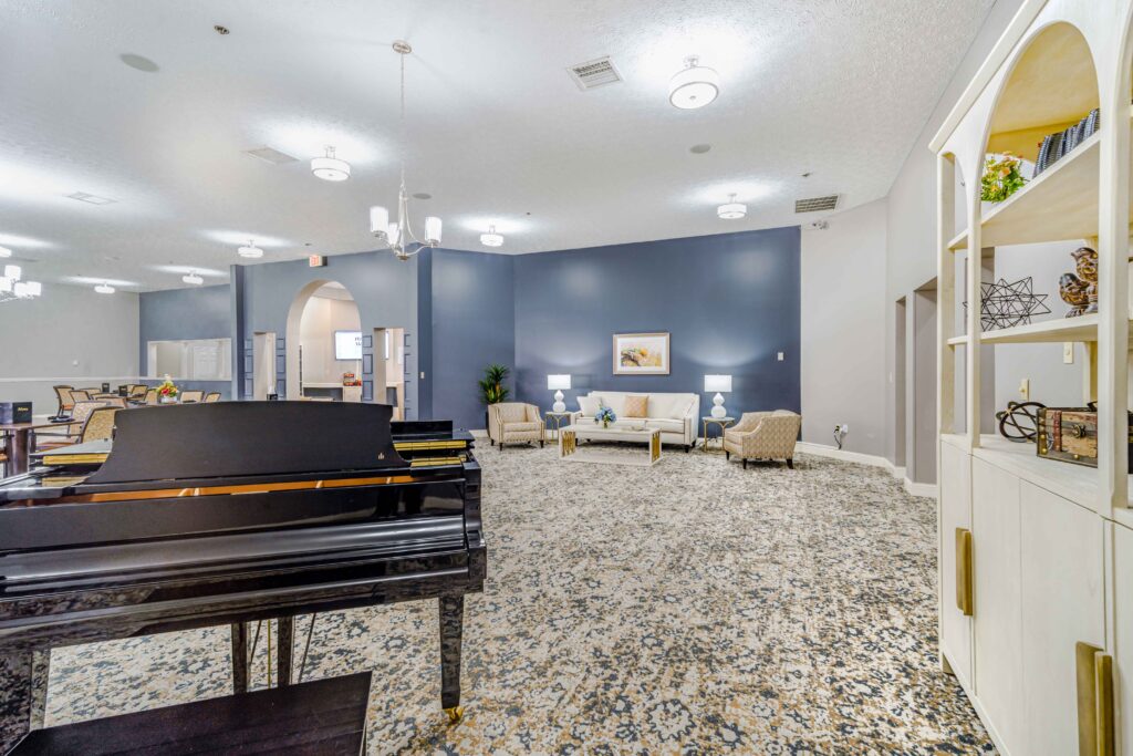 Interior shot of Inspirations of Mount Washington's social area with comfortable furniture and a baby grand piano.